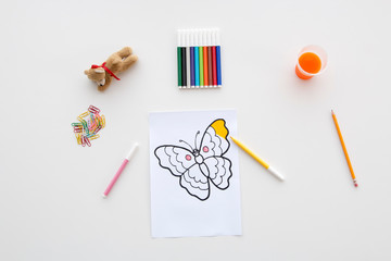 Flat lay desk for child coloring concept with draw partially colored, felt-tip pens, orange juice and a bear