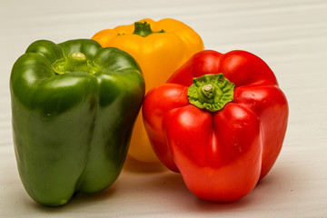 Red pepper green pepper and yellow pepper isolated against a white background