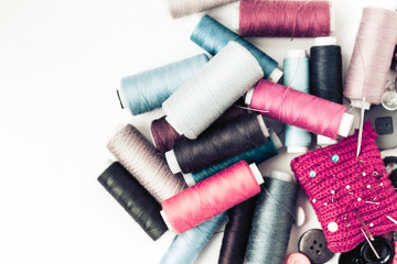 Red knitted needle pad for sewing and colored thread coils on white background with copy space for text.