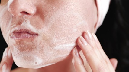 Fototapeta premium Close-up of a woman's face. The girl applies a cleansing agent and massages her.