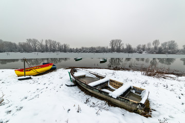 Naklejka premium Beautiful frozen river. A boats covered with snow.