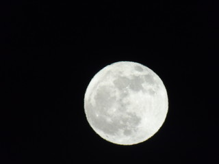Genova, Italy - 10/24/2018: An amazing photography of the full  moon over the city of Genova by night with a great clear sky in background and some stars using high zoom.