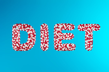 inscription diet white and red capsules on a blue background top view. concept of weight management drugs