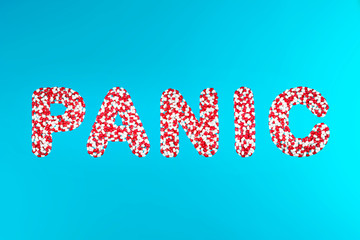 inscription panic white and red pills on a blue background top view. concept of panic-removing drugs