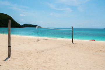 Obraz na płótnie Canvas Net Volleyball on sand beach , Sea island front view seascape sunny with tree around blue sky.