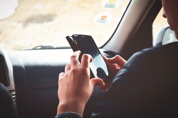 Teenager using smartphone sitting on the front passenger seat of a car. Drive, phone and technology...