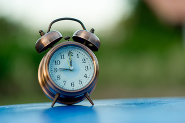 Golden alarm clock picture placed on a blue table, green background Punctual concept With copy space