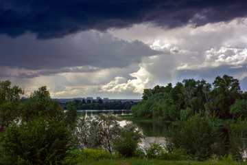 Fototapeta na wymiar huge black rain clouds over the river and the city
