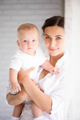Mother and child in a white room. Mom and baby boy in diaper pla