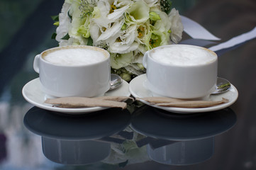 Two cups of coffee on a dark table.