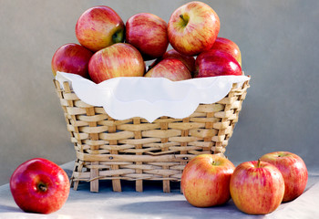 ripe red apples in a wicker basket on a gray background