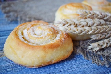 Delicious fresh buns and wheat ears on burlap.