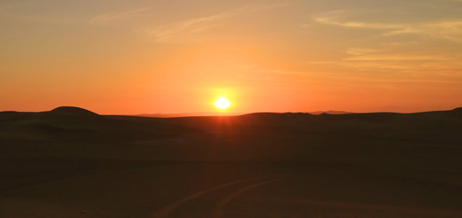 Impressive Sunset over the Sand Dunes of Huacachina Desert with the Dune Buggy Wheels Prints in the Sand, Ica region, Peru