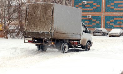 truck slips on a slippery snow-covered road in winter during a snowfall
