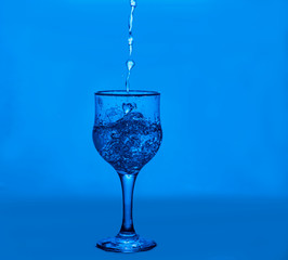 Splashes of water. Glass on a blue background. Minimal night party life concept