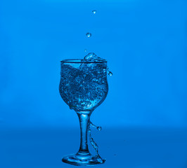 Splashes of water. Glass on a blue background. Minimal night party life concept