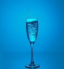 Splashes and bubbles  of water. Glass on a blue background. Minimal night party life concept