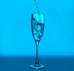 Splashes and bubbles of water. Glass on a blue background. Minimal night party life concept