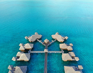 Aerial view of overwater bungalows with thatched roofs in the Bora Bora lagoon in French Polynesia