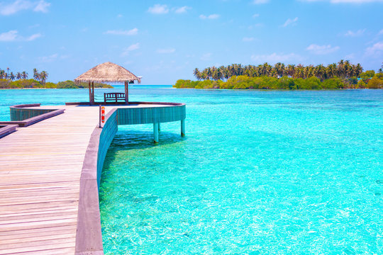 summer hot caribbean maldives vacation beach background - view on the azure blue tropical exotic sea with wood bridge and loungers and house snf on island with palms