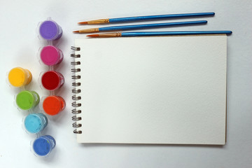 Blank spiral notebook with paint pots and paint brushes