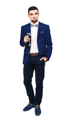 young stylish man in blue suit posing with a glass of wine