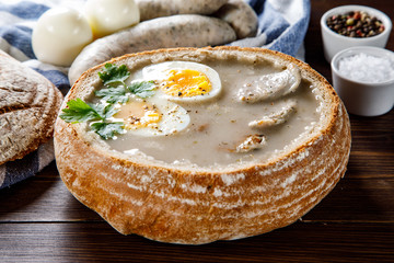 Sour rye soup in bread on wooden table