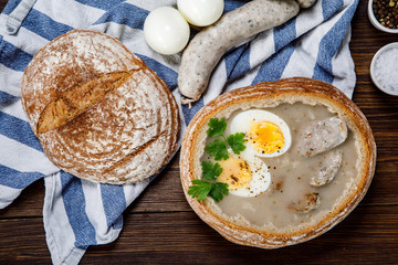 Sour rye soup in bread on wooden table