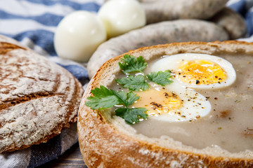 Sour rye soup in bread on wooden table