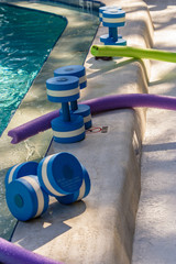 Water barbells and noodles wait at poolside as the water aerobics class begins