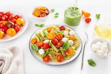 healthy fusilli pasta with pesto sauce, roasted tomatoes, mozzarella