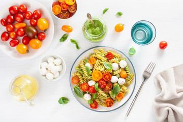 healthy fusilli pasta with pesto sauce, roasted tomatoes, mozzarella