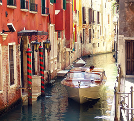 Venetian urban landscape, motorboat driving in reverse gear in a picturesque narrow canal