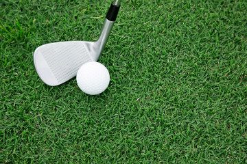 Top view of iron golf club and golf ball on the green grass