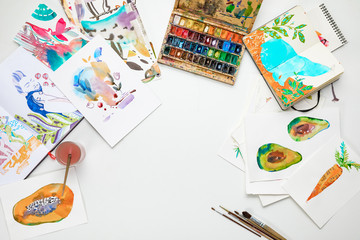 Fototapeta na wymiar top view of colorful watercolor paintings and drawing utensils