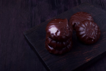 Zephyr covered with chocolate against the dark background. Dark photo