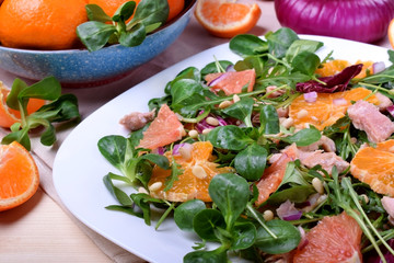 Salad with radicchio, mandarins, red oranges and canned tuna on a white plate