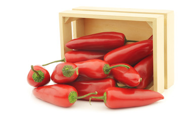 Red jalapeno peppers in a wooden box on a white background