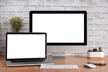 Blank screen of all in one computer and laptop computer with smart phone and cactus vase on white brick wall background