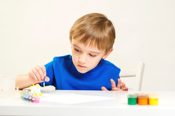 Child painting a ceramic pottery model at art class. Art school. Creative education and development. Child painting in the kindergarten. Cute little boy enjoying his painting.