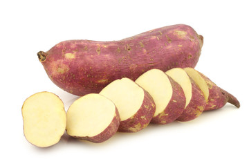 Freshly harvested sweet potato and some slices on a white background