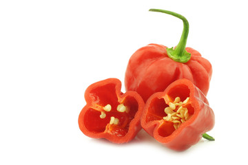 spicy hot red habanero peppers and a cut one on a white background