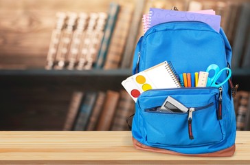 Colorful school supplies in backpack on white background