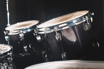 Plakat Closeup view of a drum set in a dark studio. Black drum barrels with chrome trim. The concept of live performances