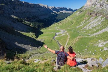 Naklejka premium Hikers looking at the glacial valley of Ordesa National Park on a sunny day