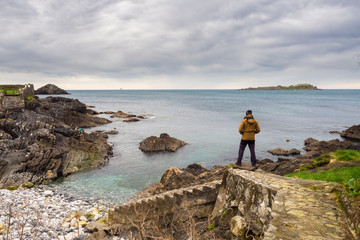 .Man looking at the coast of the Vizcaino village of Mundaca on a beautiful cloudy day