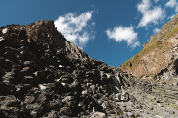 Fototapeta na wymiar Wide angle view of a rocky slope on a sunny summer day. Structural hexagonal cliffs in the North Caucasus