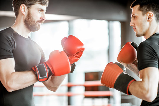 Two professional boxers in black sportswear red gloves standing together before the fight on the boxing ring