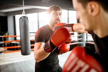 Two professional boxers in black sportswear during the fight on the boxing ring at the gym