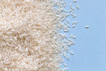 Grains of white Asian rice on blue background. Carbohydrates, healthy food, protein. Place for text.
